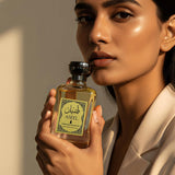 Aseel Premium Luxury Perfume for Men and Women, featured in an elegant setting, holding the bottle close to the face.