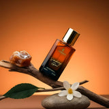 Smoking Gun Eau De Parfum bottle displayed on a wooden branch with natural elements, showcasing elegance and sophistication.