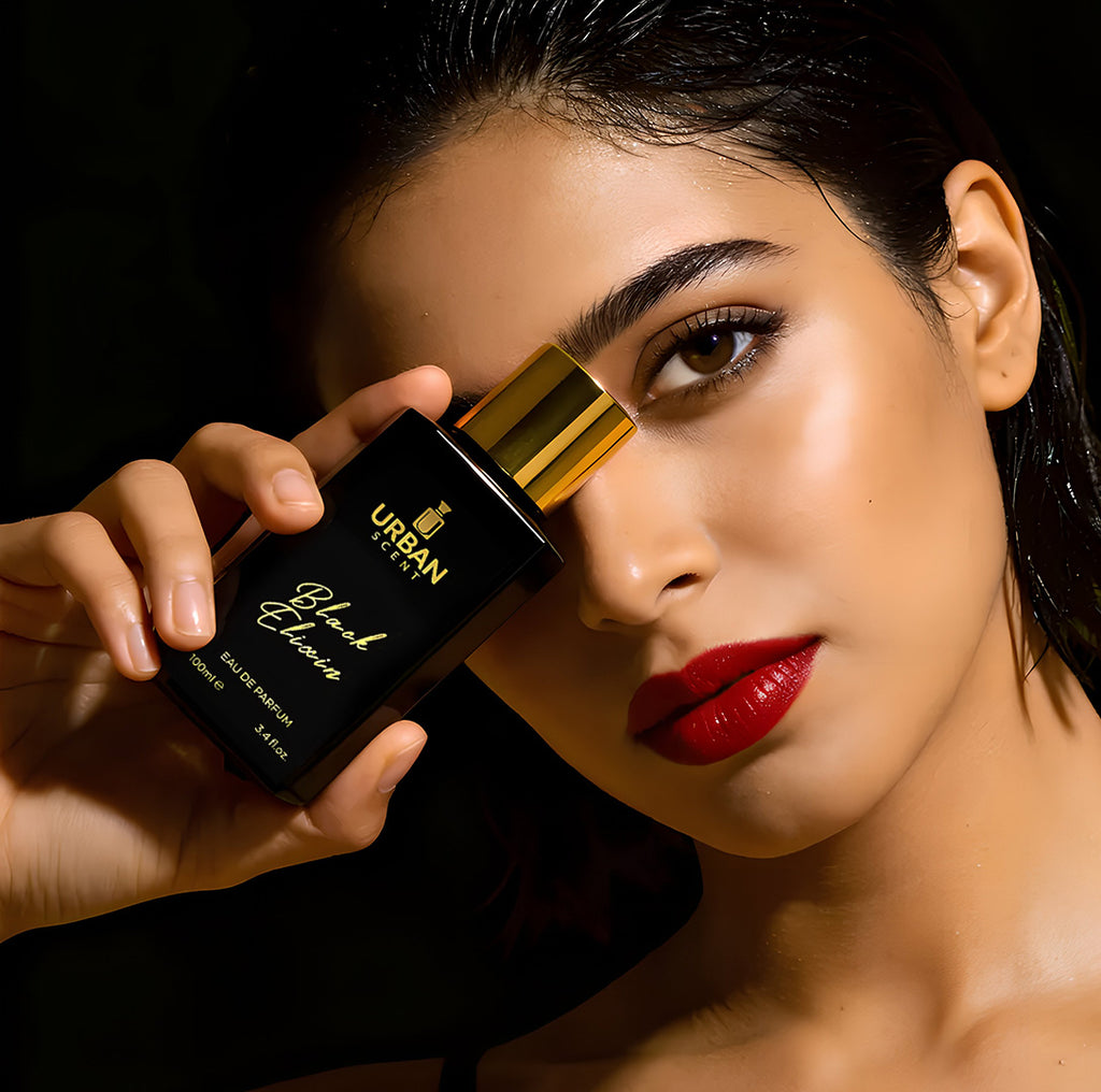 Model holding Urban Scent Black Elixir Eau De Parfum bottle, showcasing unisex fragrance in stylish packaging.